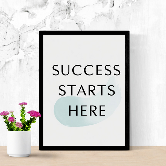 Motivational wall art print with black text 'Success starts here' on a white background, featuring a subtle light blue watercolor brushstroke