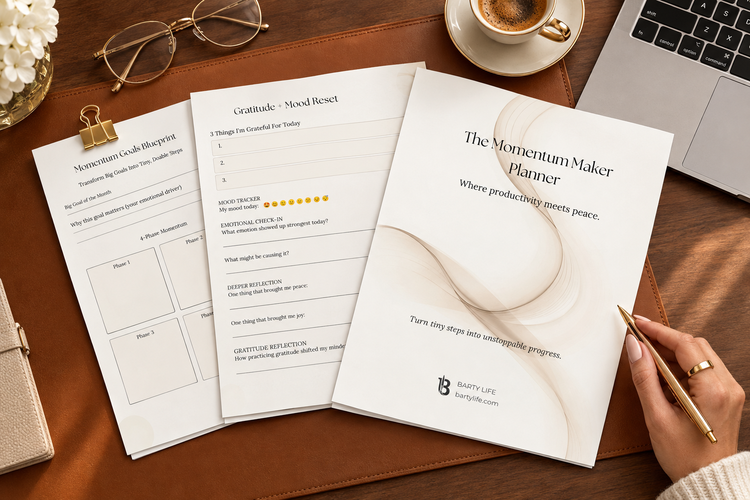 Printed Momentum Maker Planner pages fanned out on a walnut desk with leather desk pad